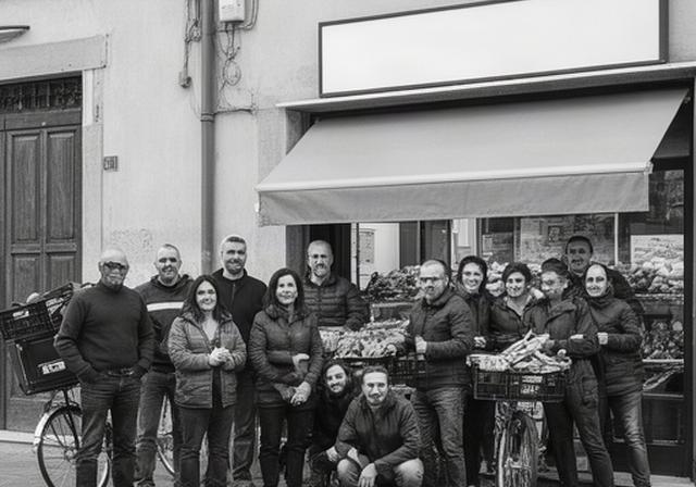 Squadra locale di consegna riunita davanti a un negozio di quartiere a Faenza